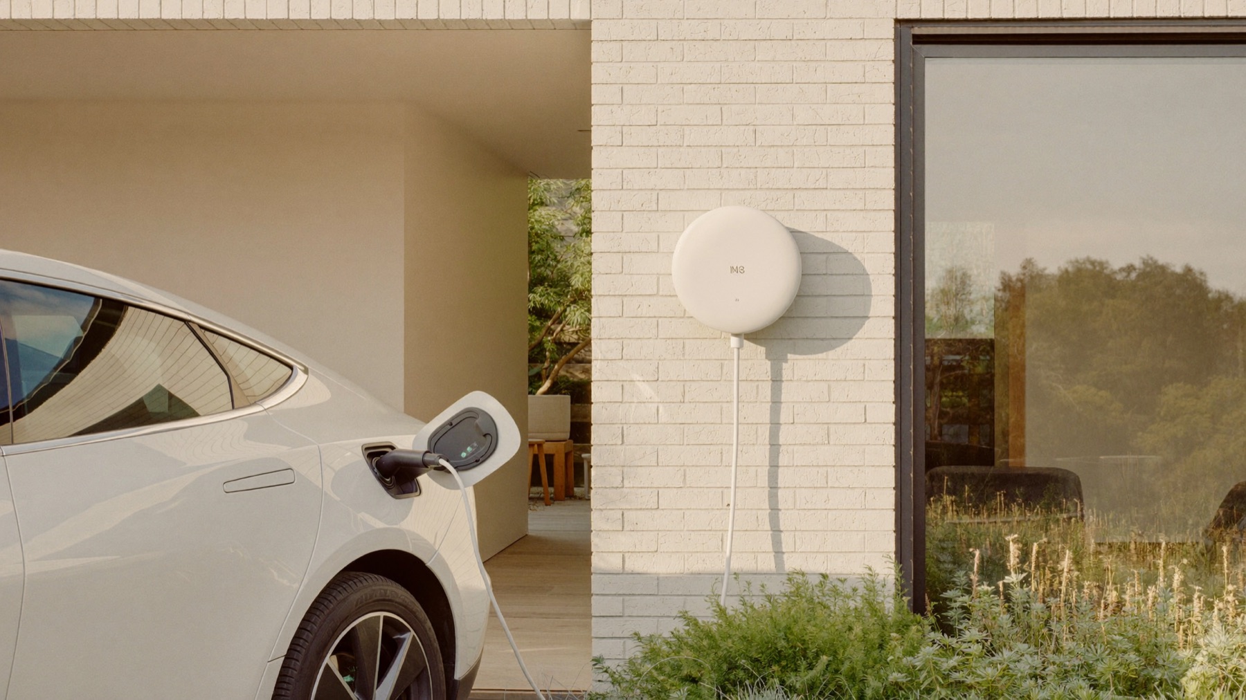 Elektrische auto laadt op aan een witte laadpaal bij een woning